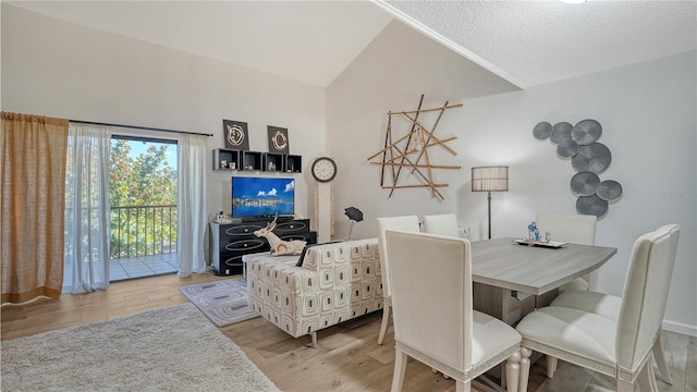 dining area featuring a textured ceiling, light hardwood / wood-style flooring, and vaulted ceiling