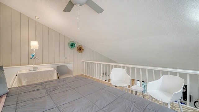 bedroom with ceiling fan, wood walls, and vaulted ceiling