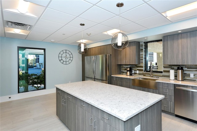 kitchen featuring a wealth of natural light, a center island, stainless steel appliances, and decorative light fixtures