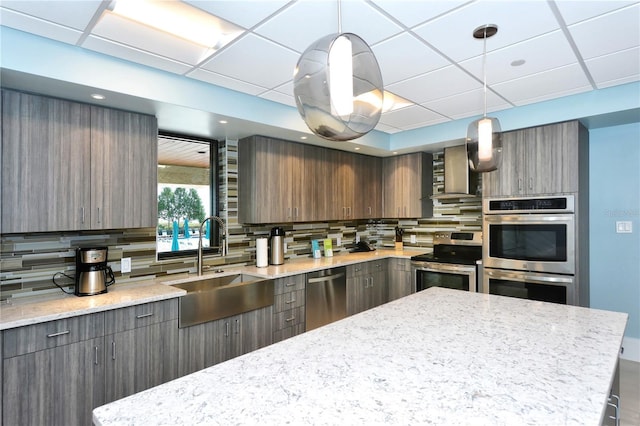 kitchen with decorative backsplash, sink, pendant lighting, and appliances with stainless steel finishes