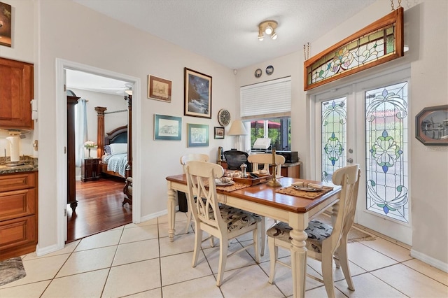 tiled dining room with ceiling fan, french doors, and a textured ceiling