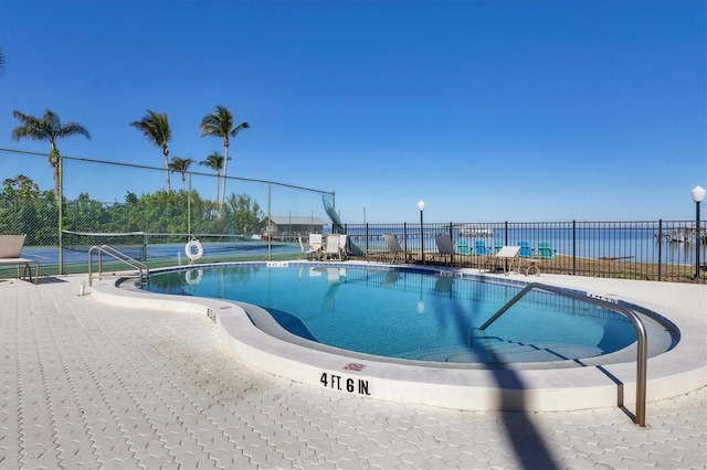 view of swimming pool with a water view and tennis court