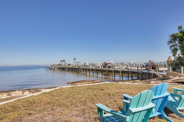 view of dock with a lawn and a water view