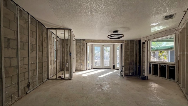 miscellaneous room featuring french doors, a textured ceiling, and a wealth of natural light