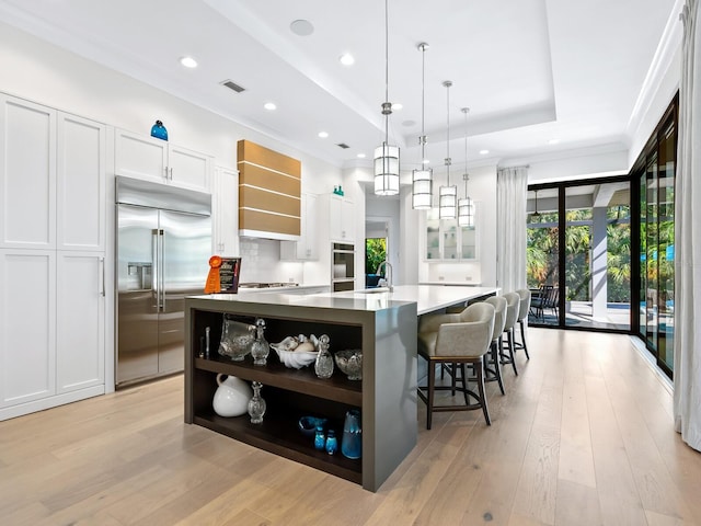 kitchen featuring custom exhaust hood, stainless steel appliances, white cabinetry, hanging light fixtures, and a large island