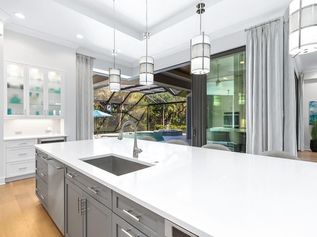 kitchen featuring pendant lighting, gray cabinetry, sink, light hardwood / wood-style floors, and white cabinetry