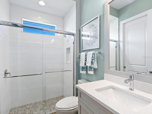 bathroom featuring vanity, a shower with shower door, and toilet