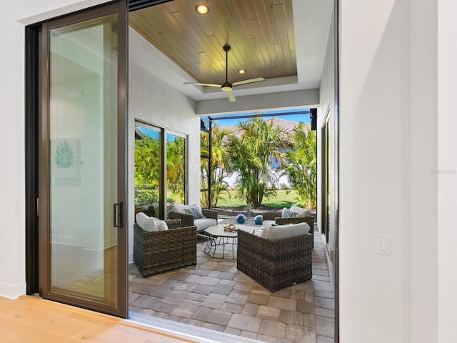 sunroom with ceiling fan, a raised ceiling, and wooden ceiling