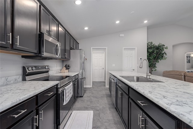 kitchen with light stone counters, sink, stainless steel appliances, and vaulted ceiling