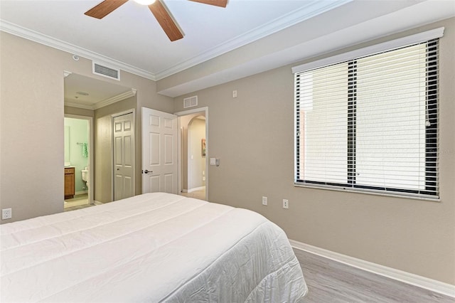 bedroom with ensuite bath, ceiling fan, ornamental molding, multiple windows, and wood-type flooring