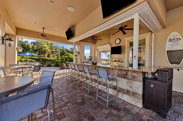 view of patio with ceiling fan and a bar