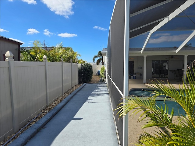 view of patio / terrace featuring glass enclosure, ceiling fan, and a pool