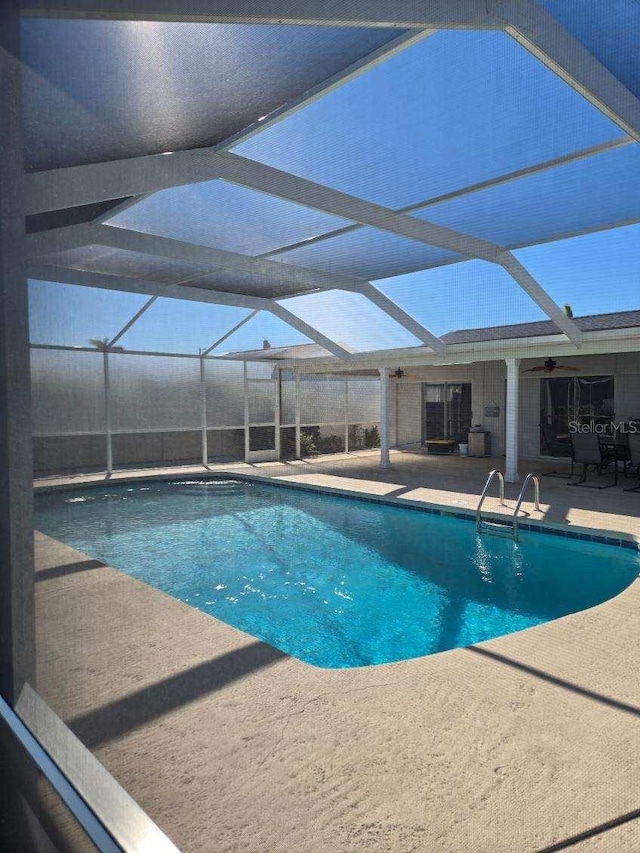 view of pool with a patio area, ceiling fan, and glass enclosure