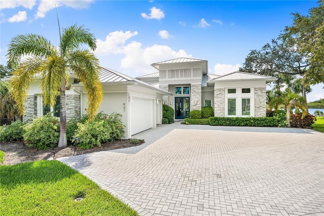 931 Bayshore Rd, Nokomis, FL 34275 - view of front facade featuring stone siding, a standing seam roof, an attached garage, decorative driveway, and french doors