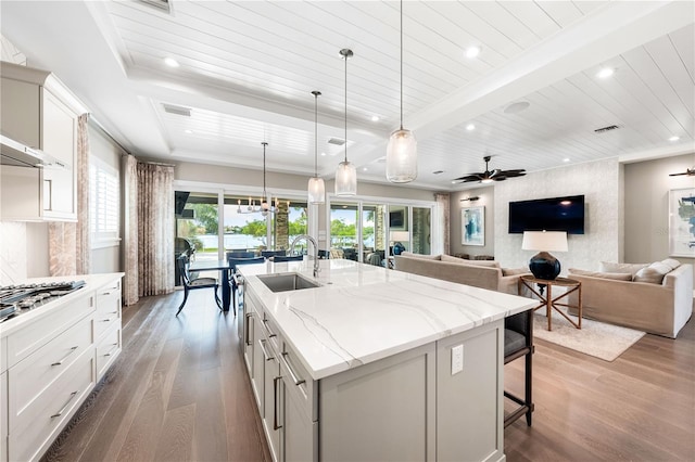 kitchen featuring ceiling fan, sink, hardwood / wood-style floors, a center island with sink, and white cabinets