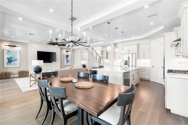 dining area featuring beamed ceiling, an inviting chandelier, light hardwood / wood-style flooring, and crown molding