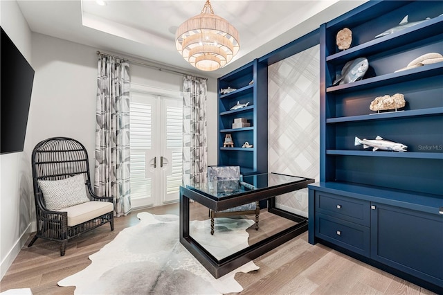 office space featuring a chandelier, built in shelves, light hardwood / wood-style flooring, and french doors