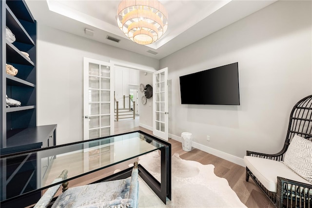 office with a raised ceiling, hardwood / wood-style floors, and french doors