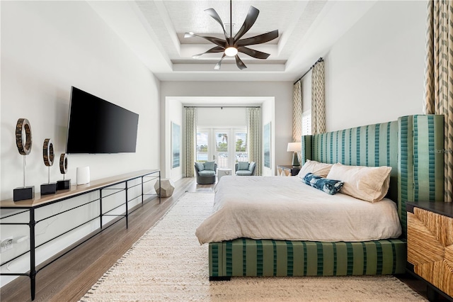 bedroom featuring hardwood / wood-style floors, a tray ceiling, and ceiling fan