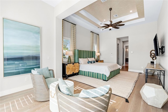 bedroom featuring a raised ceiling, ceiling fan, a towering ceiling, and hardwood / wood-style flooring