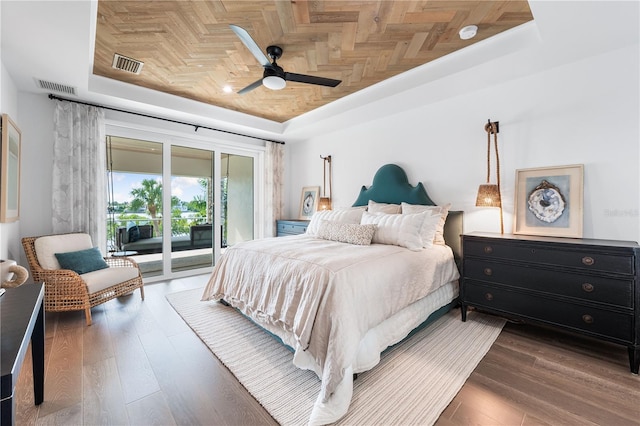 bedroom featuring access to exterior, a raised ceiling, ceiling fan, and dark wood-type flooring