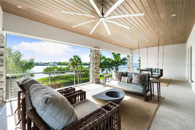 sunroom with ceiling fan, a water view, and wooden ceiling