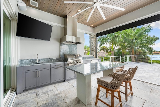 view of patio featuring area for grilling, ceiling fan, exterior kitchen, and a wet bar