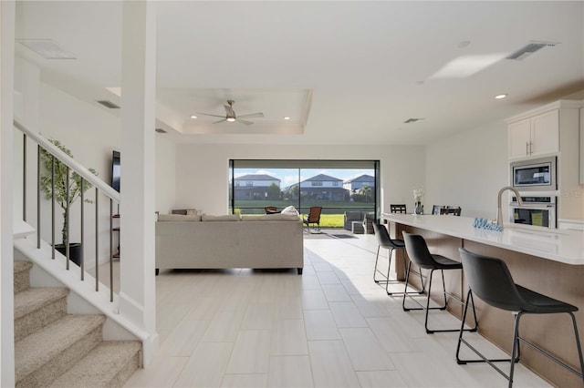 living room with a tray ceiling and ceiling fan