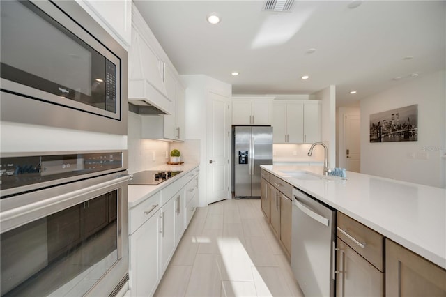 kitchen with sink, stainless steel appliances, light tile patterned floors, decorative backsplash, and white cabinets