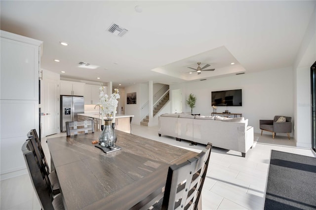 dining room featuring a raised ceiling, ceiling fan, and sink