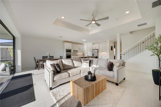 living room featuring ceiling fan, a raised ceiling, and sink