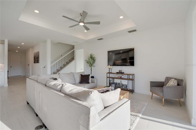 living room featuring a raised ceiling and ceiling fan