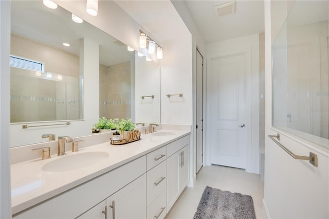 bathroom with tile patterned flooring, vanity, and a tile shower