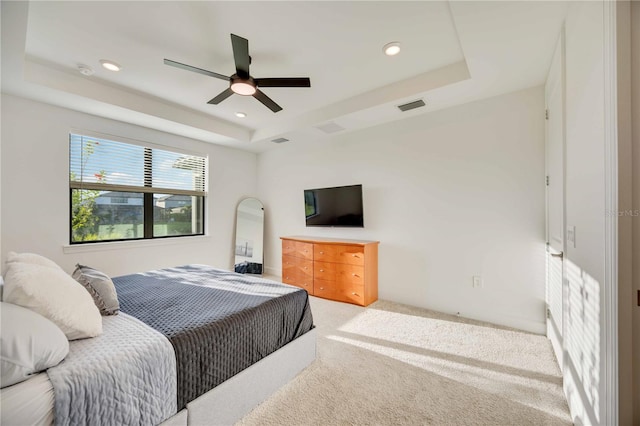 carpeted bedroom featuring a tray ceiling and ceiling fan