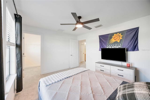 carpeted bedroom with ceiling fan, a walk in closet, and a closet