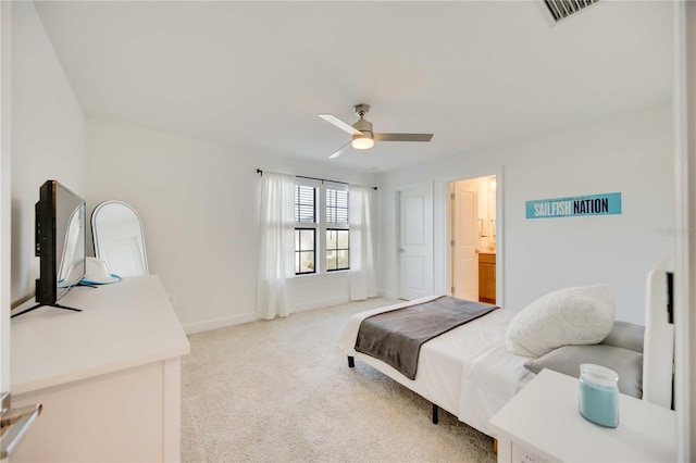 bedroom with ceiling fan, light colored carpet, and ensuite bathroom