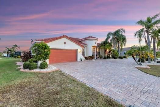 mediterranean / spanish-style home with a yard and a garage