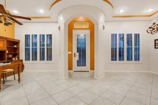 entryway with a tray ceiling, ceiling fan, and light tile patterned floors