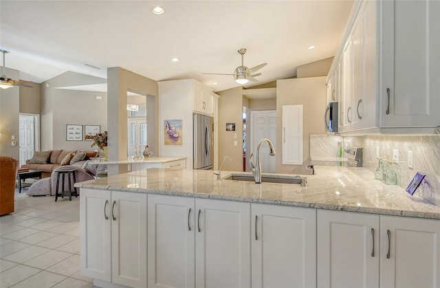 kitchen featuring kitchen peninsula, appliances with stainless steel finishes, light stone countertops, sink, and white cabinets