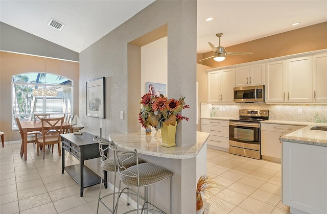 kitchen with kitchen peninsula, white cabinetry, stainless steel appliances, and lofted ceiling