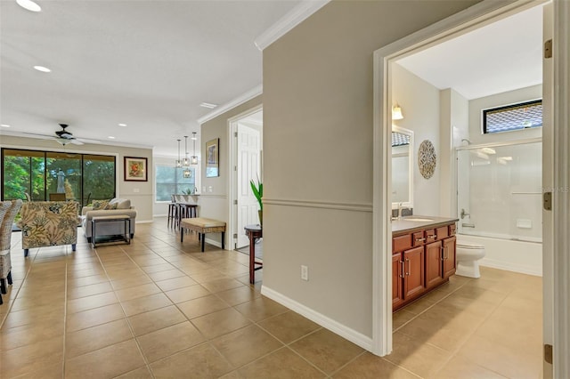 corridor featuring a chandelier, light tile patterned floors, sink, and ornamental molding