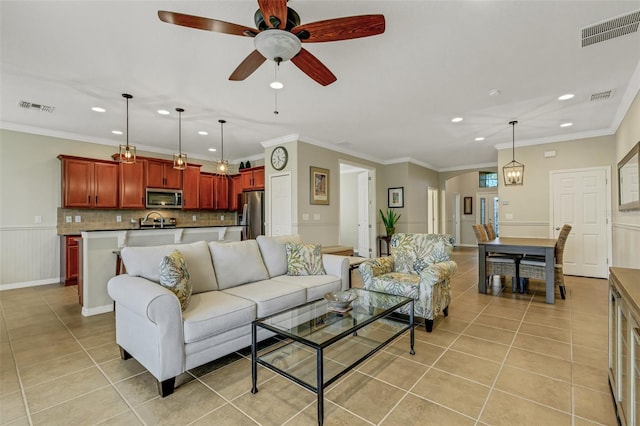 living room featuring ceiling fan, sink, light tile patterned floors, and ornamental molding