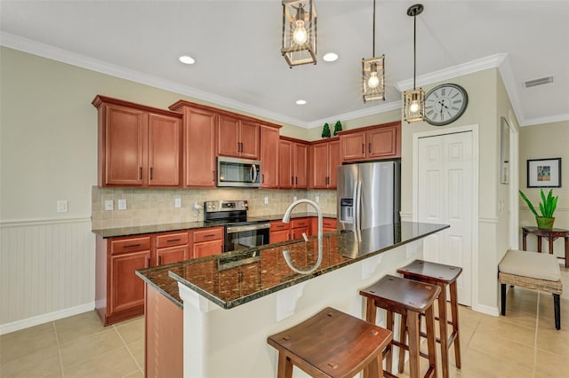 kitchen with ornamental molding, stainless steel appliances, and a center island with sink