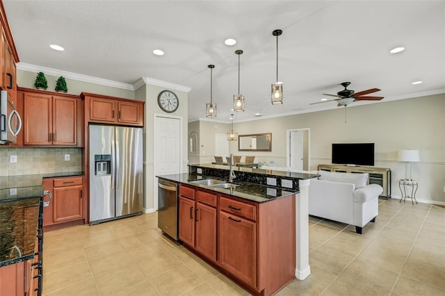 kitchen featuring ceiling fan, sink, stainless steel appliances, an island with sink, and decorative light fixtures