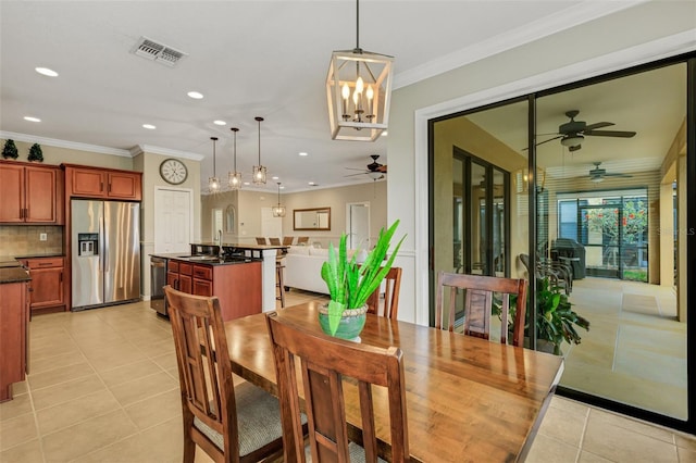 tiled dining room featuring ceiling fan with notable chandelier, sink, and crown molding