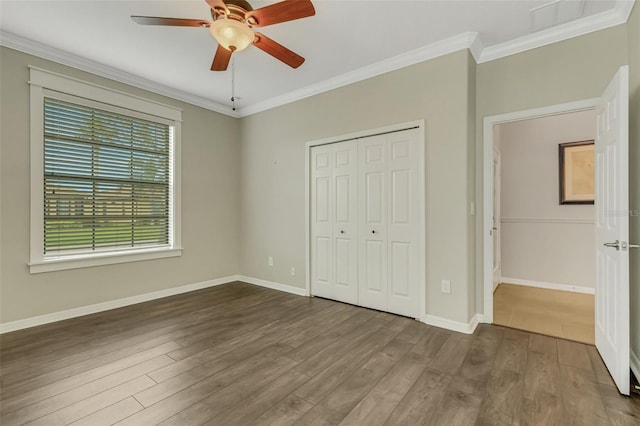 unfurnished bedroom with crown molding, ceiling fan, a closet, and dark wood-type flooring