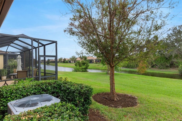 view of yard with glass enclosure, cooling unit, and a water view