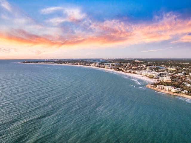 aerial view at dusk with a beach view and a water view