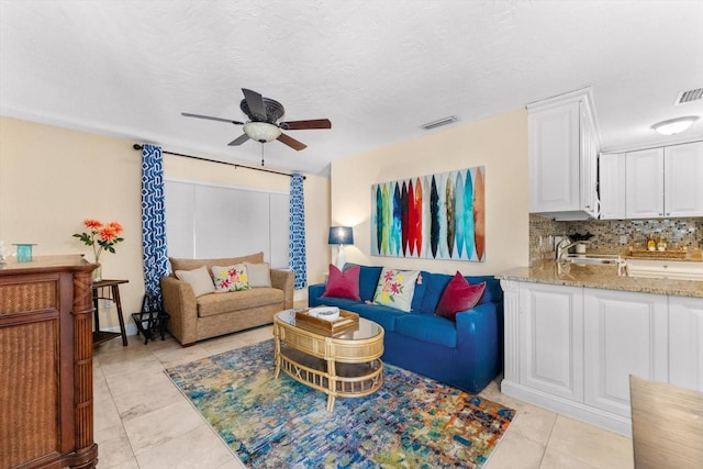 tiled living room with ceiling fan, sink, and a textured ceiling