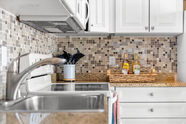 kitchen featuring backsplash, light stone countertops, and white cabinets